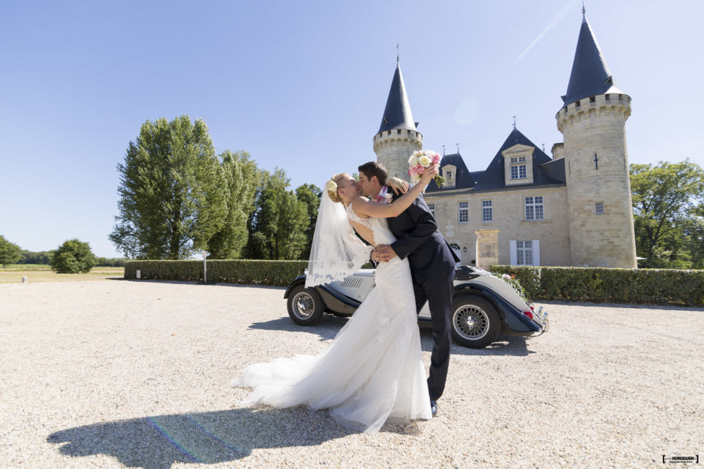 Sebastien et Maryia s'embrassent devant le chateau d'Agassac à Ludon Médoc près de Bordeaux, belle robe de mariée