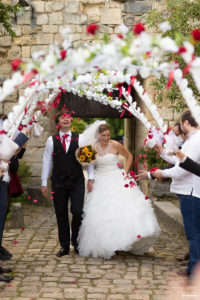 Les mariés sont accueillis par une haie d'honneur de couronnes de fleurs au chateau médiéval de Langoiran Sébastien Huruguen photographe de Mariage à Bordeaux