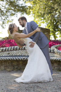 Jolie mariée dans sa robe de mariage pose dans les bras de son mari en costume gris penchée en arrière au parc majolan de blanquefort lors de leur séance photo trash the dress avec le celebre photographe de mariage a bordeaux Sebastien Huruguen amour love wedding