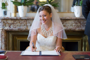 mariee-en-robe-blanche-et-voile-souriante-durant-la-signature-mairie-de-bordeaux-mariage-civil-sebastien-huruguen-photographe-professionnel