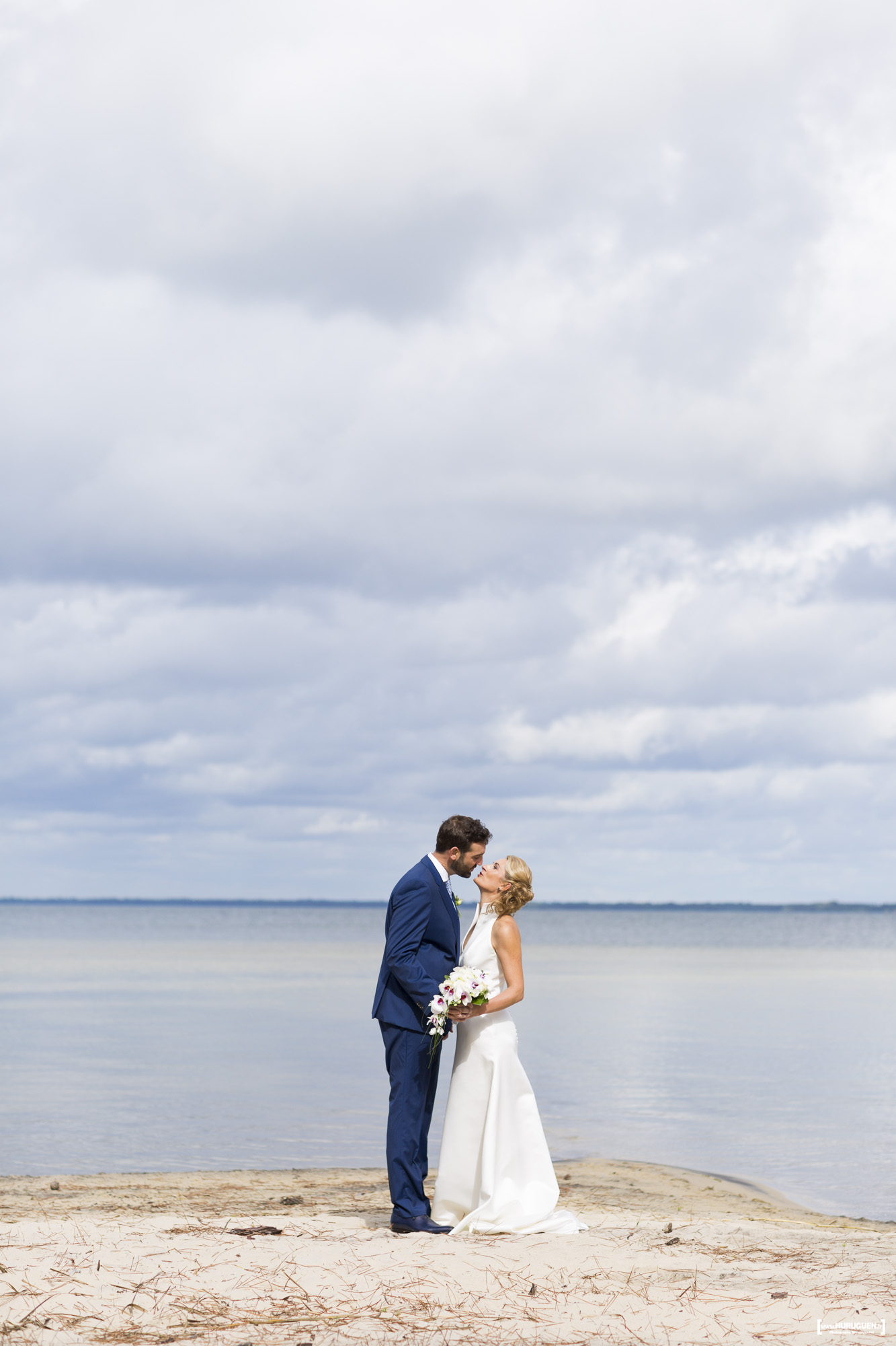 un joli couple de jeunes mariés qui s'embrassent sur la plage au bord de l'eau, photo de mariage au lac de Carcans Maubuisson
