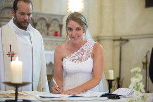 la mariee signe sur l'autel a l'église d'Yvrac a cote du pretre ceremonie de mariage religieux catholique bordeaux sebastien huruguen jolie robe de mariage