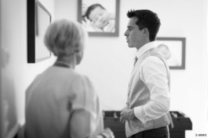 Le futur mari se prépare devant le miroir avec l'aide de sa mère habillage photographe mariage bordeaux Sébastien Huruguen