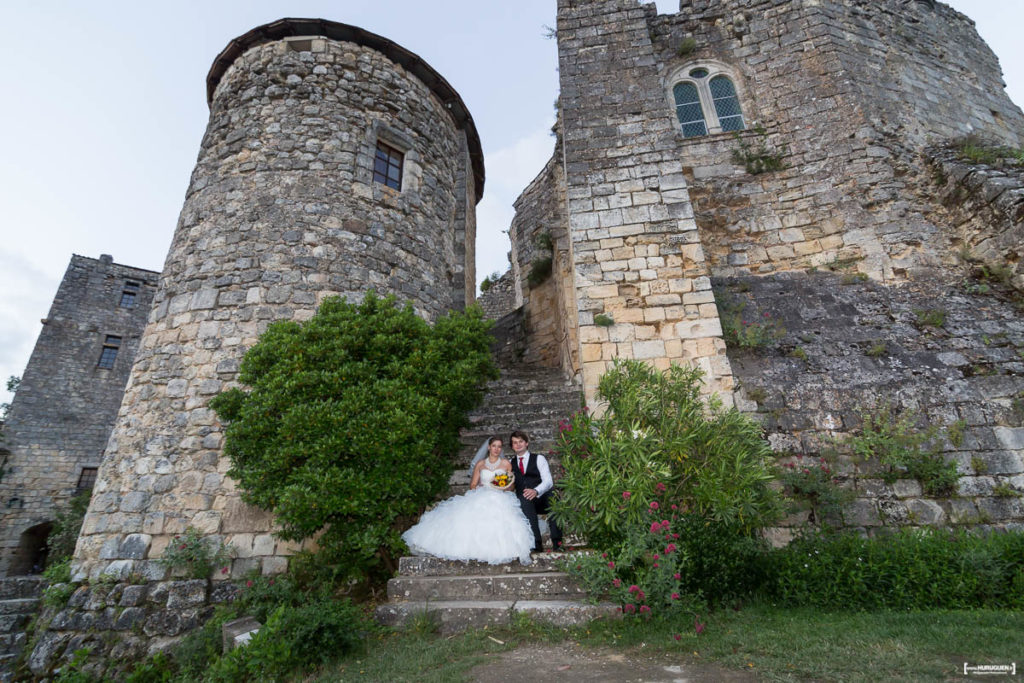 couple de jeunes mariés posant sur les marches du chateau médiéval de Langoiran