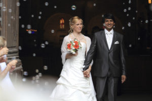 Mariés qui sortent de l'église sous les bulles et la joie franco indien sebastien huruguen photographe mariage bordeaux