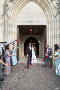 Sortie des mariés sous les jets de pétéles de roses rouges et blanches