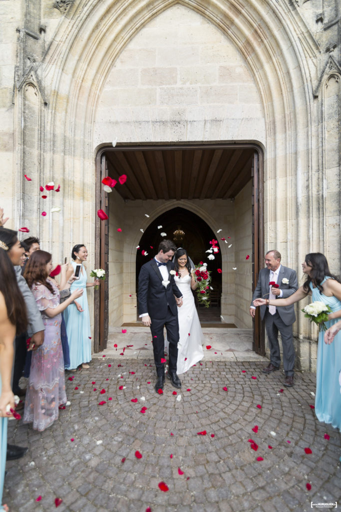 Sortie des mariés à l'église de Macau près de Bordeaux avec lancés de pétales de roses rouges et blanches Sébastien Huruguen photographe mariage Bordeaux