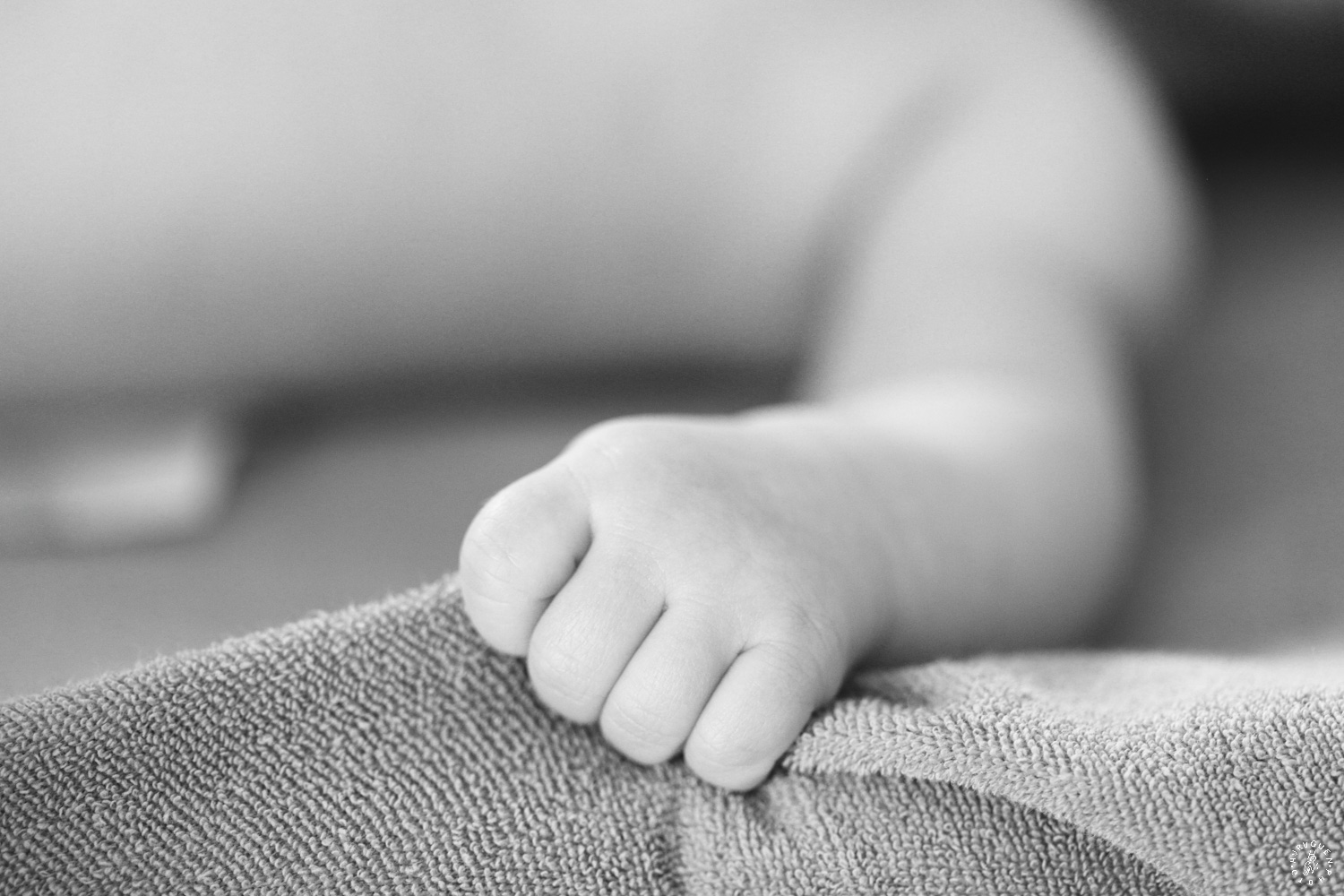 main de bébé en noir et blanc serrant une couverture dans ses petits doigts