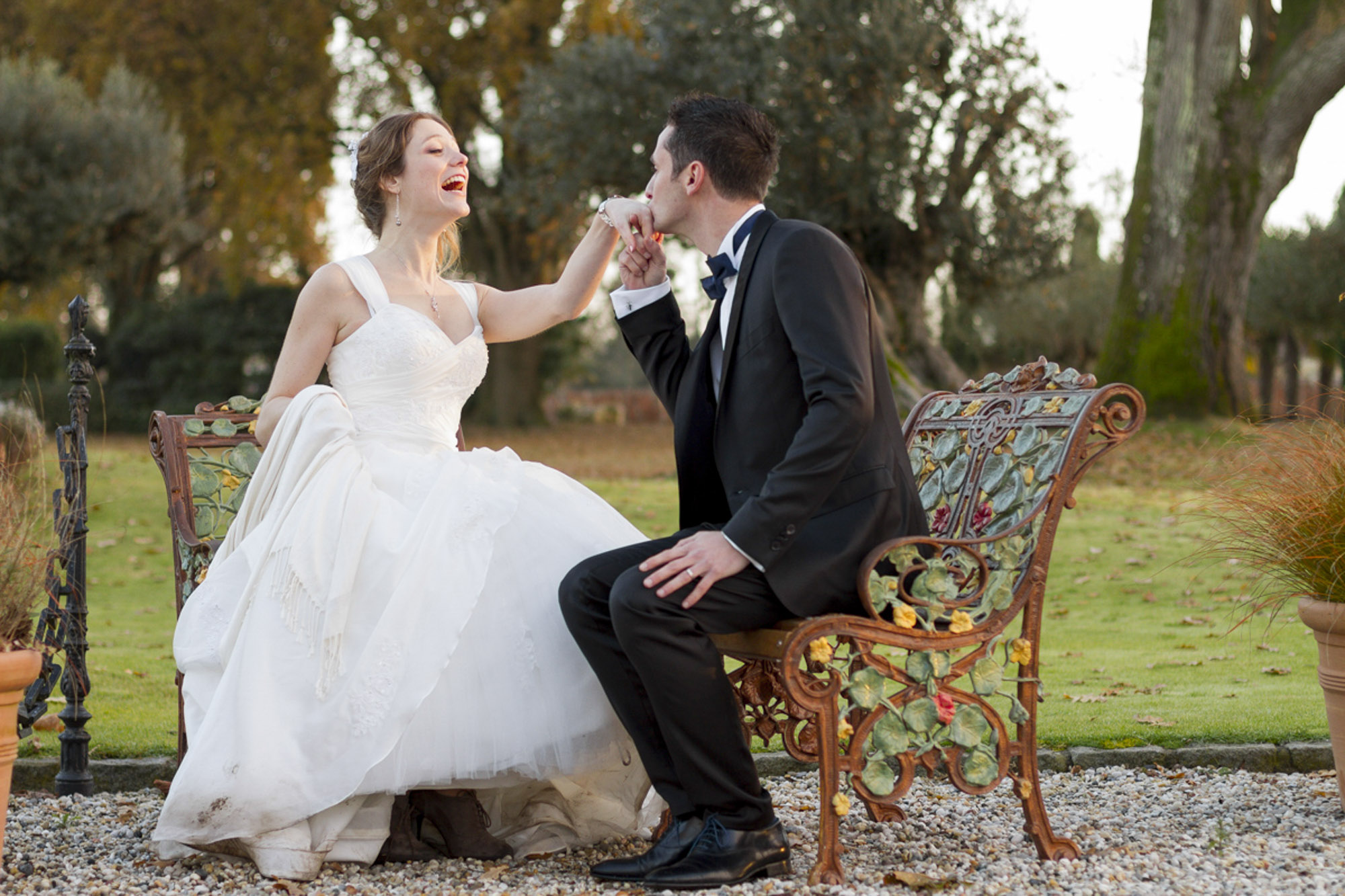 Couple de jeunes mariés souriants et complices dans le jardin du domaine du Château Pape-Clément à Pessac en Gironde sous l'oeil du photographe de mariage à Bordeaux Sébastien Huruguen