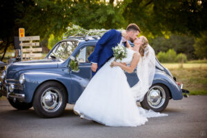 Jeunes mariés s'embrassant lors de leur arrivée au Château Larrivet Haut-Brion à Léognan devant une Renault 4CV de 1955.