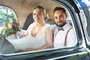 Mariés complices à l'arrière d'une voiture de collection Citroën Traction pour un mariage rétro-chic au Château Villegeorges.