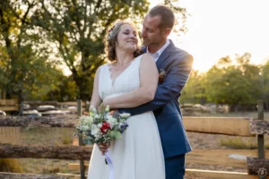 Portrait de la mariée souriante et radieuse dans les bras du marié lors d'une séance couple au coucher de soleil, mariage champêtre dans la forêt de Saint-Magne, Gironde par Sébastien Huruguen Photographe.